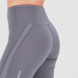 Close-up of a person wearing high-waisted gray athletic leggings with a subtle striped side detail, highlighting fit and smooth texture.