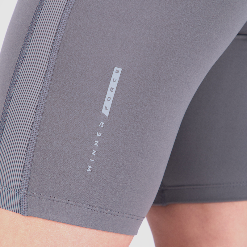 Close-up of a person's leg wearing gray athletic shorts. The shorts feature vertical stripes and the text "WINNER FORCE" printed on the side.