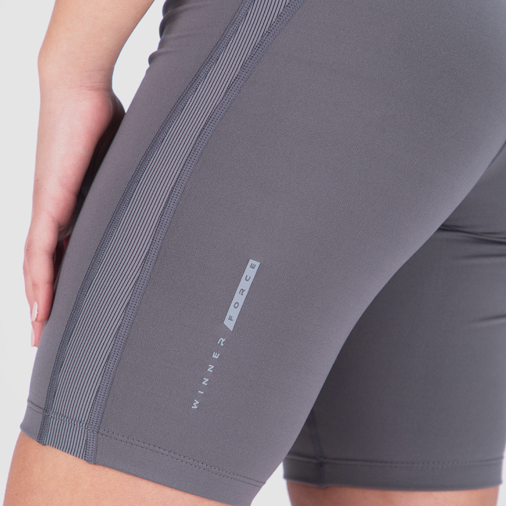 Close-up of someone wearing gray compression shorts with vertical striped detail. The words "Winner Force" are visible, suggesting a sporty, active vibe.