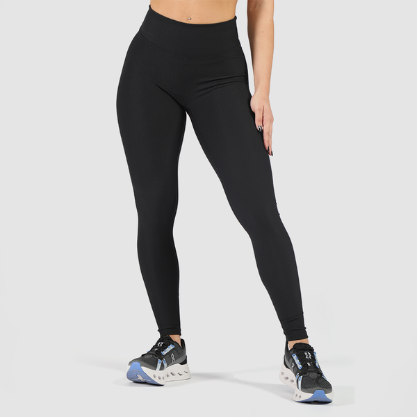a fit woman wearing legging black and shoes ,the background is light grey