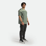 a fit man wearing t-shirt agave green with logo and pants black , plus shoes 