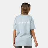 a back view for fit woman stand at right and wearing t-shirt blue  with logo and legging grey 