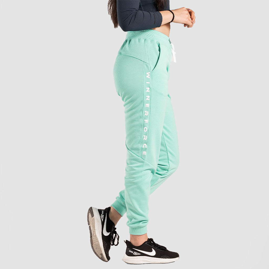 a fit woman stand at right  and wearing  pants aqua  with sneakers 