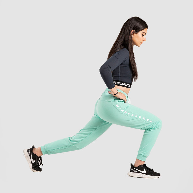 a fit woman stand with pose sports and wearing crop top black with pant aqua ,plus she wearing  sneakers black 