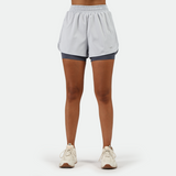 a fit woman wearing  arctic ice blue  short 2 in 1 with shoes white ,plus the background is light grey 