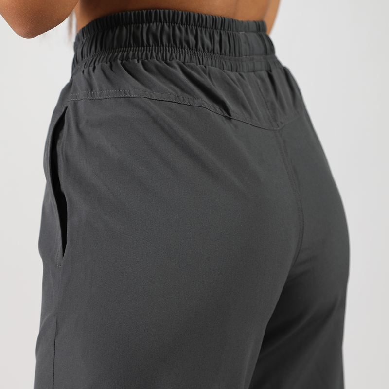 a back view for  fit woman wearing pants grey ,plus the background is light grey 