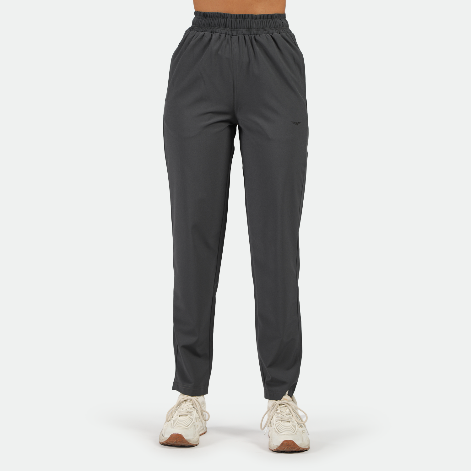 a fit woman wearing pant grey with white athletic shoes ,plus the background is light grey  