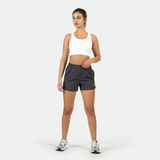 a fit woman wearing sports bra white  with short grey ,and she wearing shoes ,plus the background is light grey 