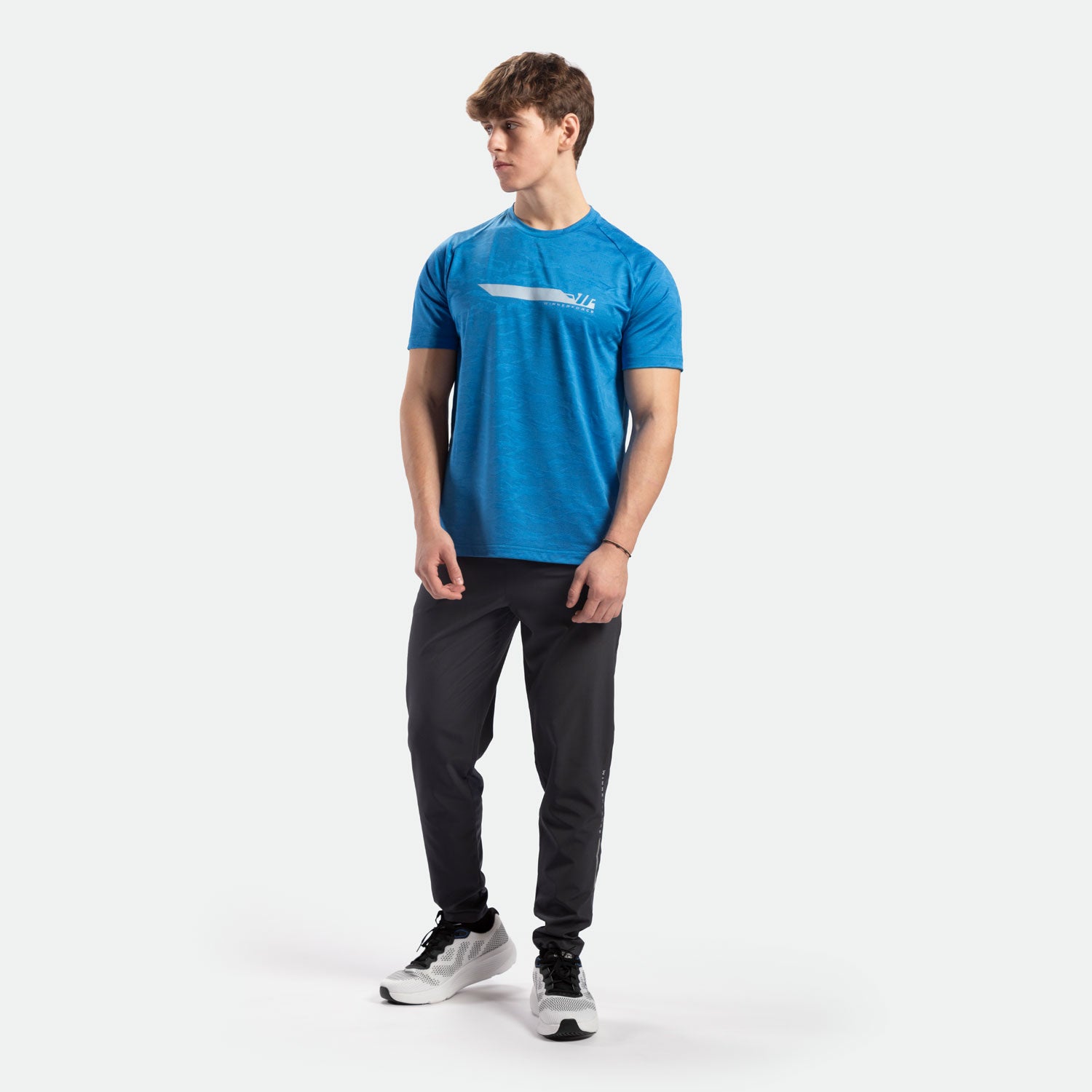 a fit man stand at right and wearing t-shirt camo azure blue with logo and pants black ,plus shoes