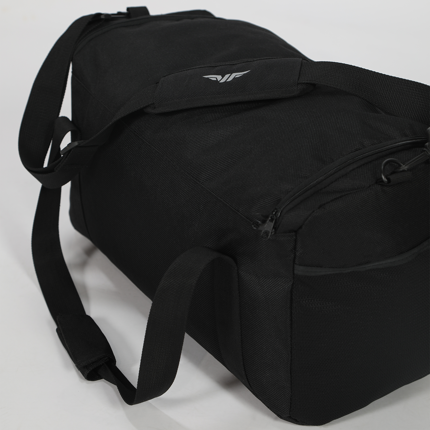 Black duffel bag with reinforced shoulder strap and zipper pocket on white background. Minimalist design with subtle logo, conveying functionality.