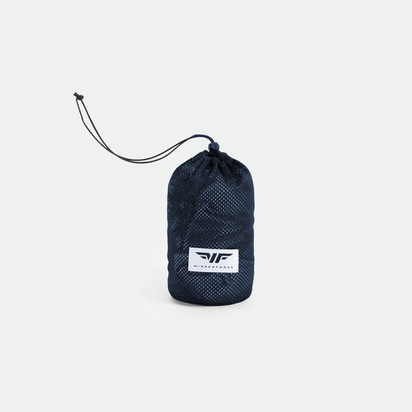 A compact navy blue drawstring bag with a mesh texture and a white logo patch sits against a light gray background. It conveys a sporty, minimalist vibe.
