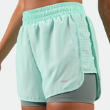 close up view for fit woman wearing  beach glass blue short 2 in 1,plus the background light grey 