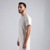 A man in profile wearing a plain white short-sleeve crewneck t-shirt and matching white pants, and the hand in the pants 