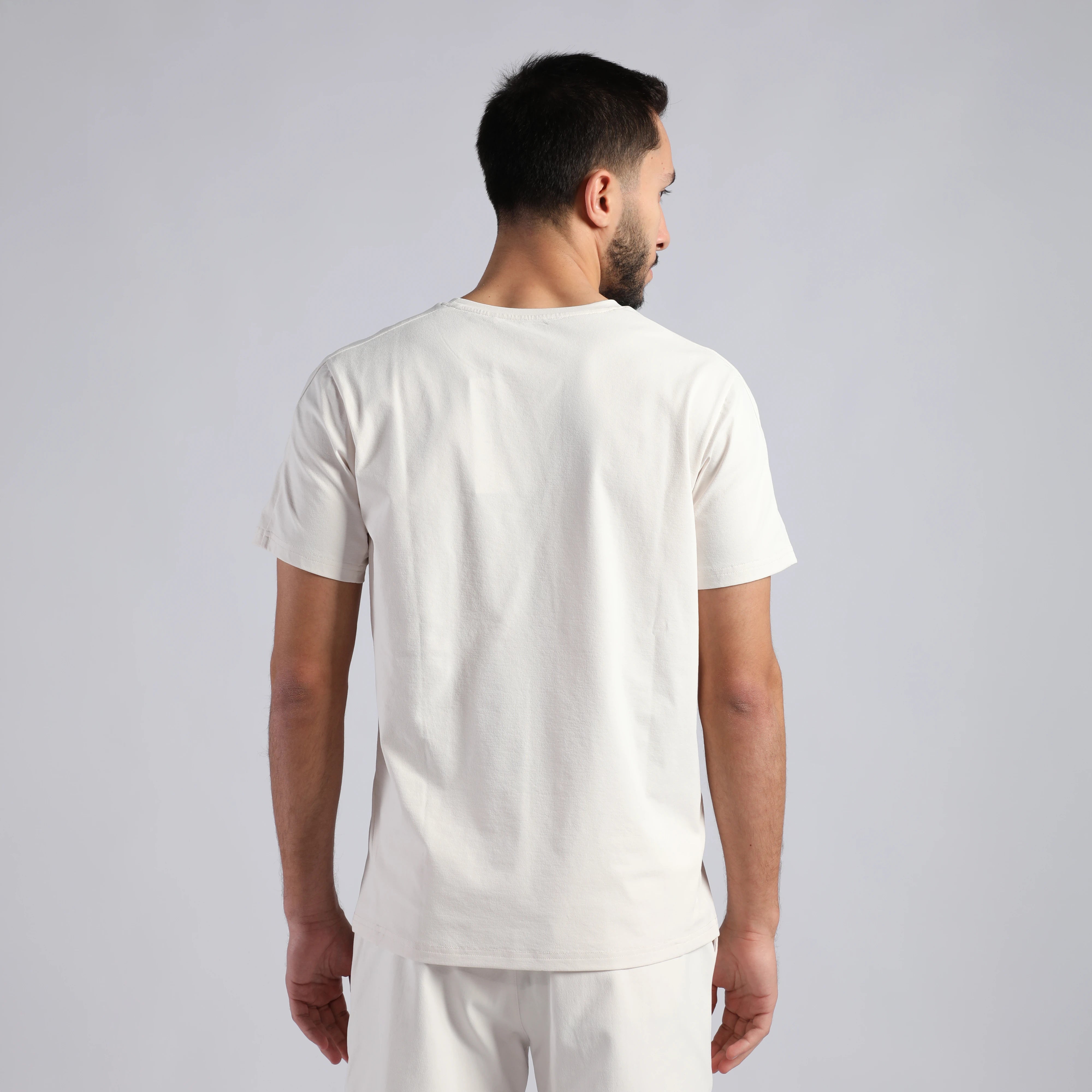 a fit man stand at lift and wearing t-shirt white with pants white 