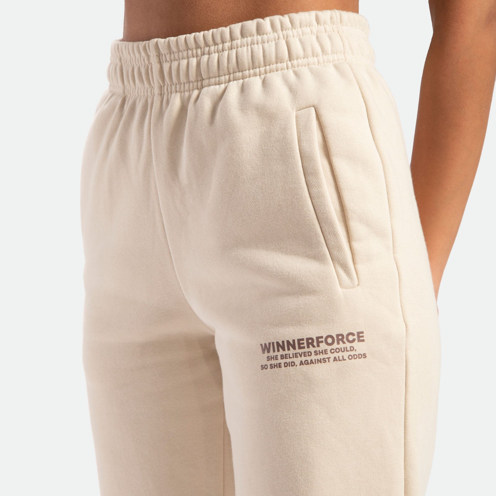 close up view for pocket beige of pant with logo brown ,plus the background is light grey 