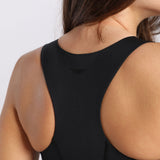 Close-up of a woman's back wearing a black racerback tank top. The fabric contours smoothly, conveying motion and fitness. Hair flows over her shoulder.