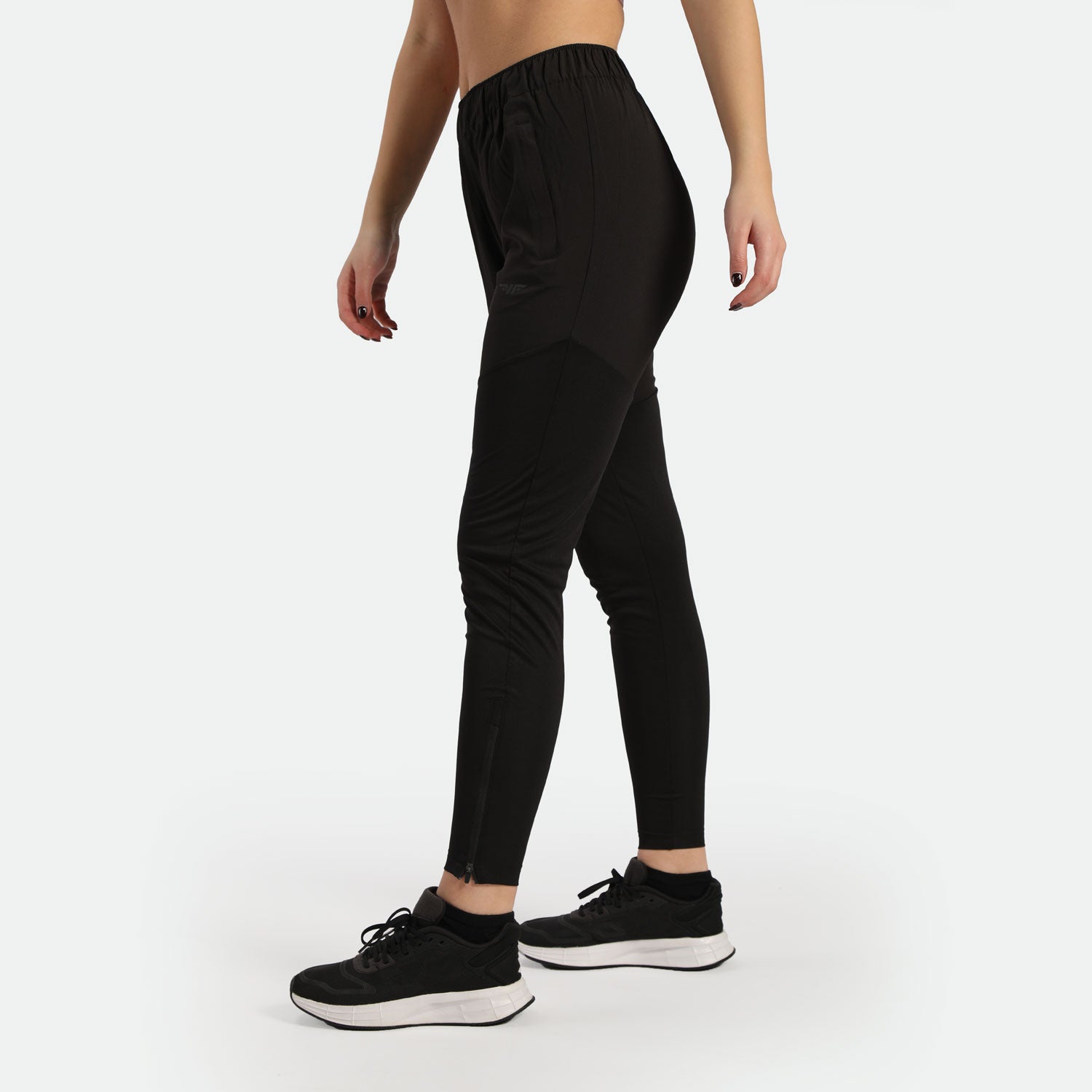 a fit woman stand at right and wearing sneakers black 