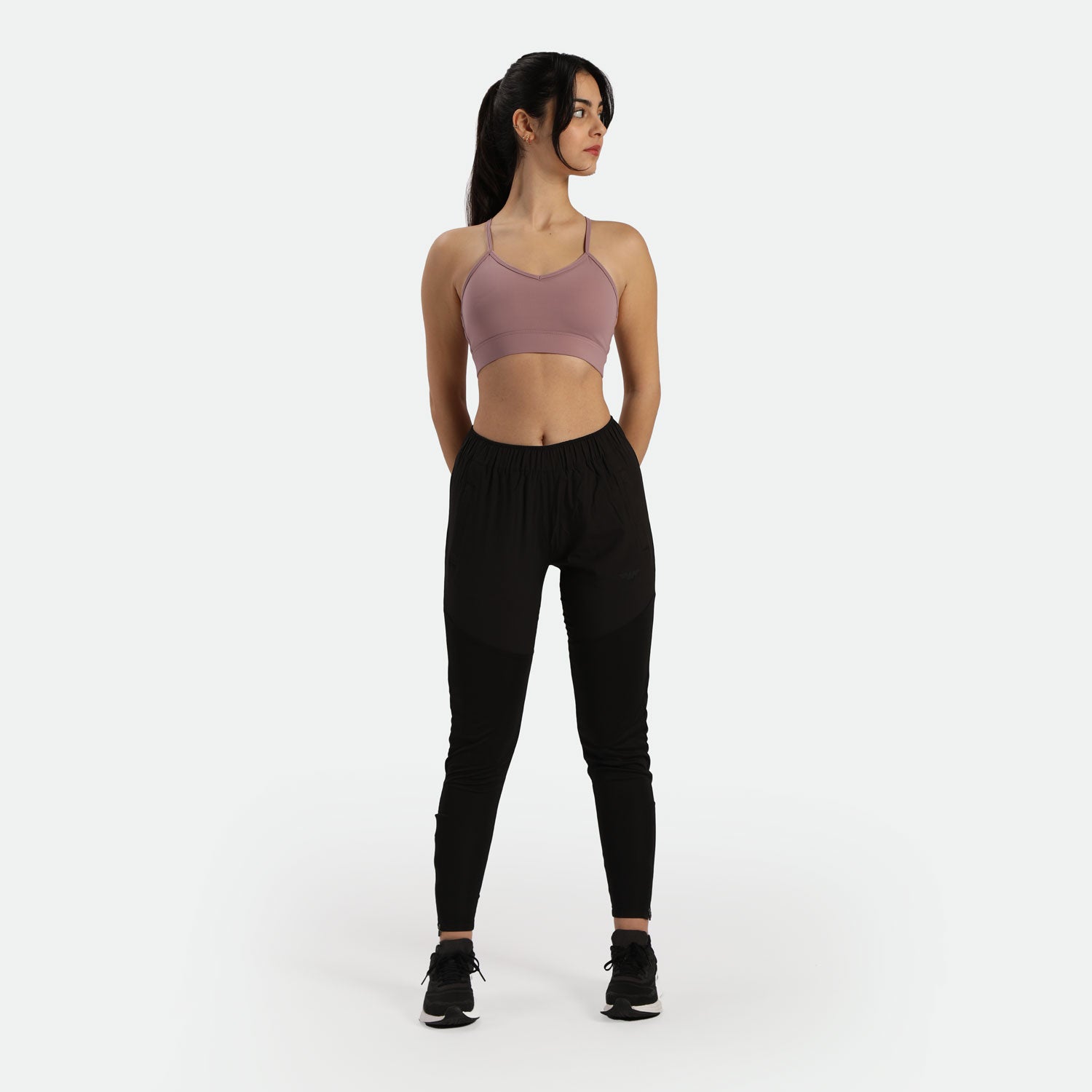 a fit woman wearing bra purple  with pants and sneakers 