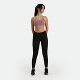 a fit woman wearing bra purple  with pants and sneakers 