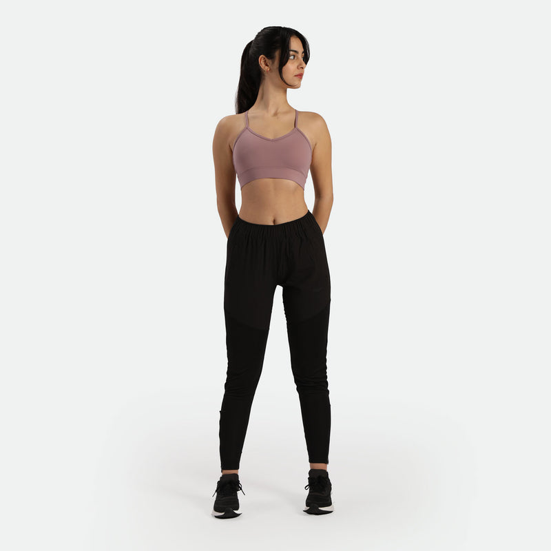 a fit woman wearing bra purple  with pants and sneakers 