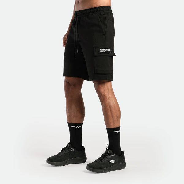 a fit man wearing short black with  pocket and logo ,plus the shoes and socks black 