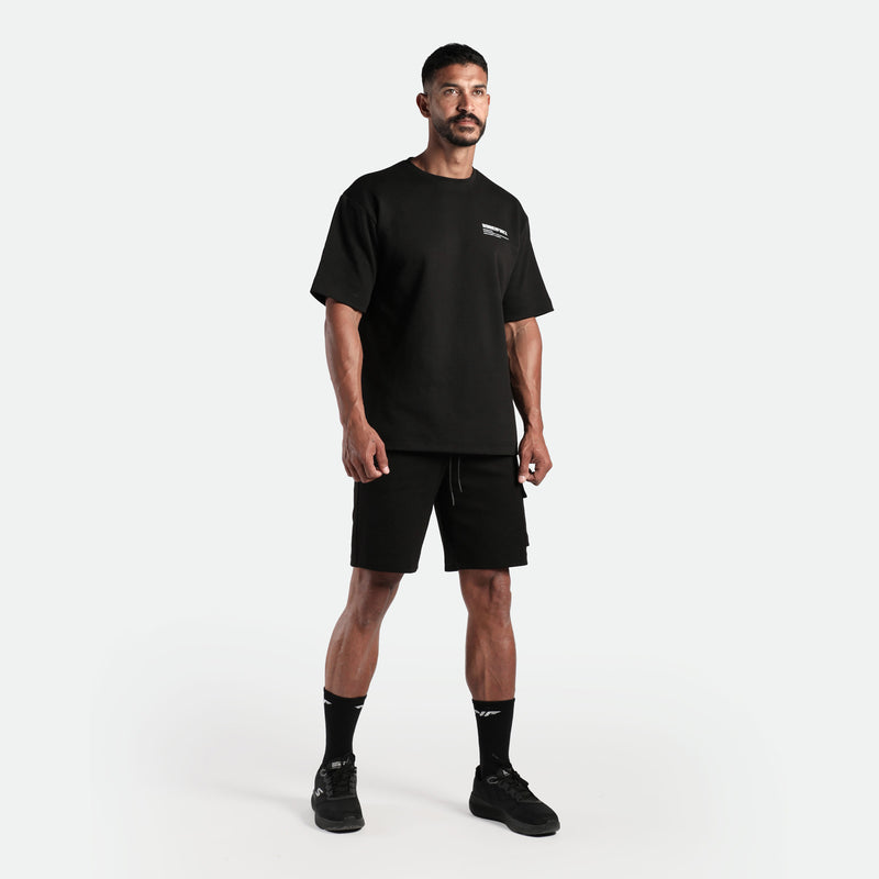 a fit man wearing matching set black  t-shirt and short , plus he wearing socks  and shoes black 