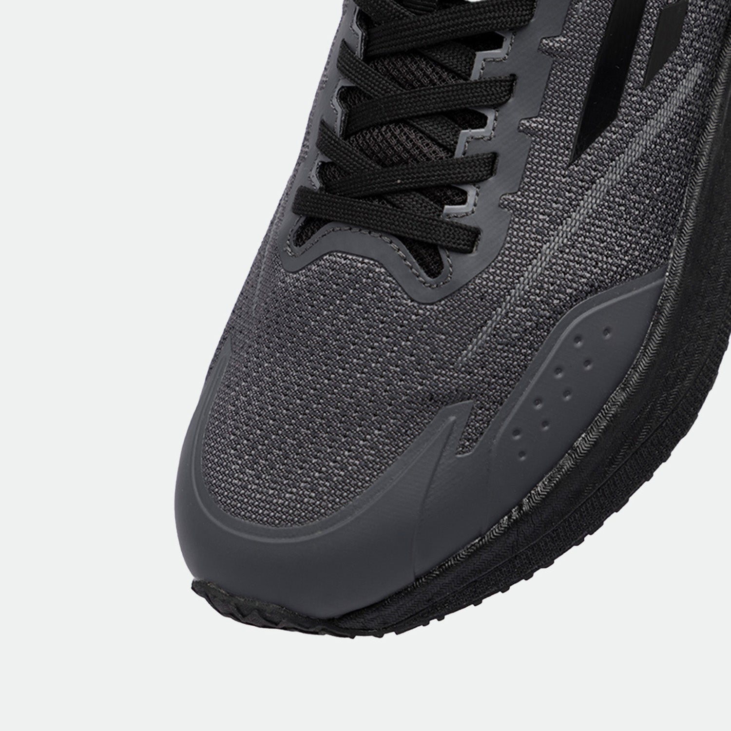 Close-up of a sleek, dark gray running shoe, featuring a textured mesh upper, black laces, and a durable sole. The design conveys a modern, athletic style.