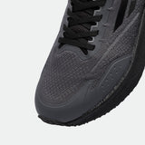 Close-up of a sleek, dark gray running shoe, featuring a textured mesh upper, black laces, and a durable sole. The design conveys a modern, athletic style.