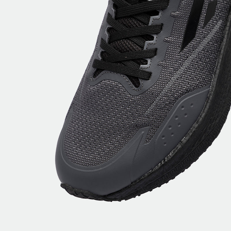 Close-up of a sleek, dark gray running shoe, featuring a textured mesh upper, black laces, and a durable sole. The design conveys a modern, athletic style.