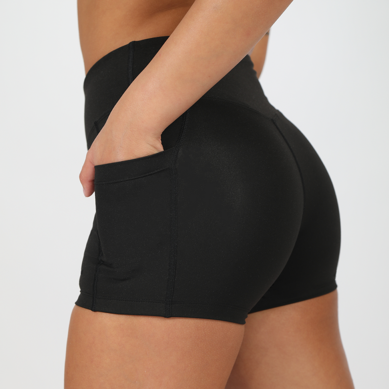 a fit woman stand at right and wearing short black ,plus the background is light grey 
