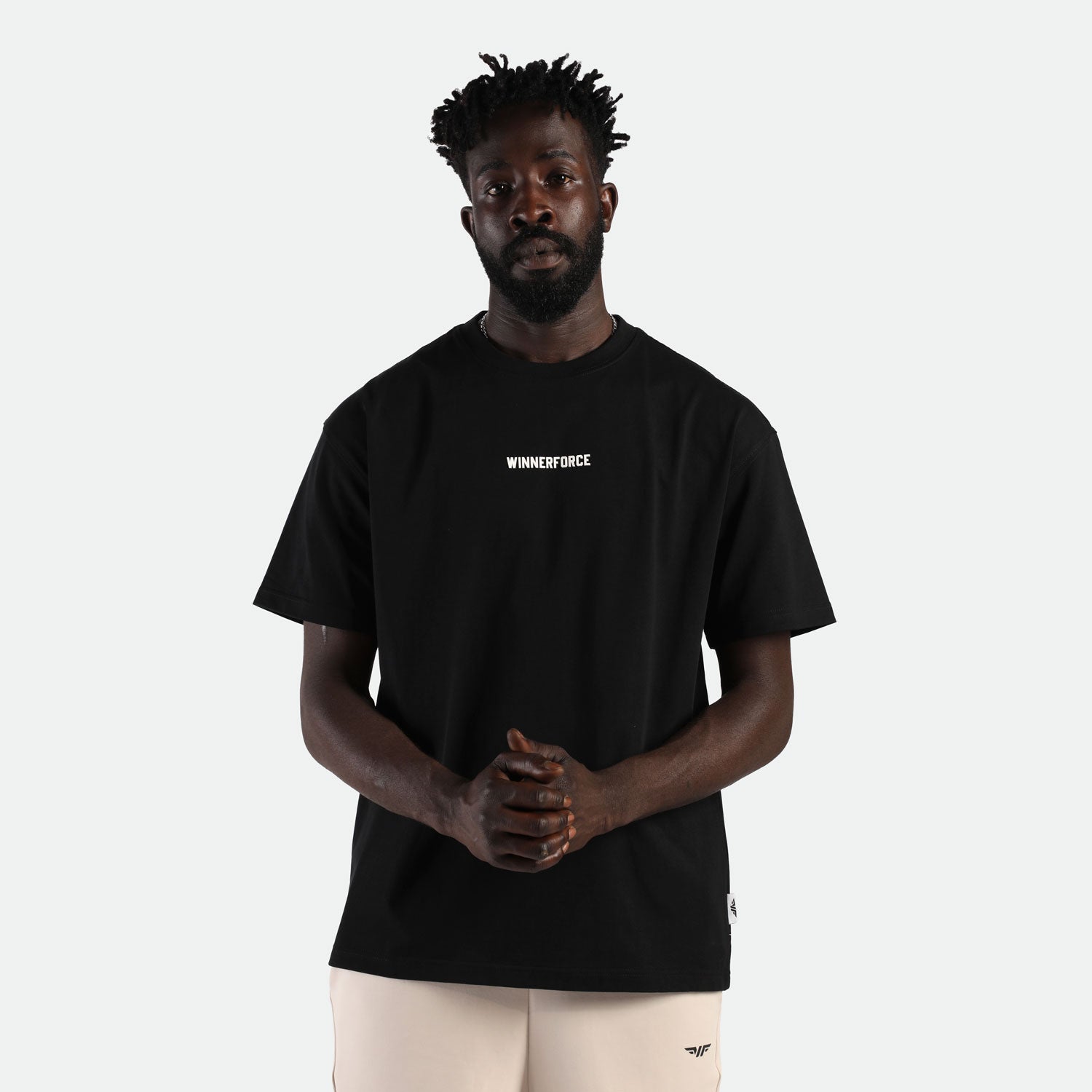 a fit man stand with confidence and look at the camera ,he wearing t-shirt black with short beige