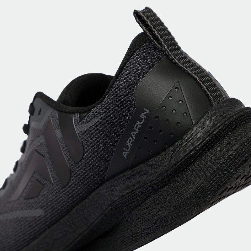 Close-up of a sleek, black athletic shoe from the heel angle, showcasing a textured, breathable mesh design and subtle branding text "AurA Run."