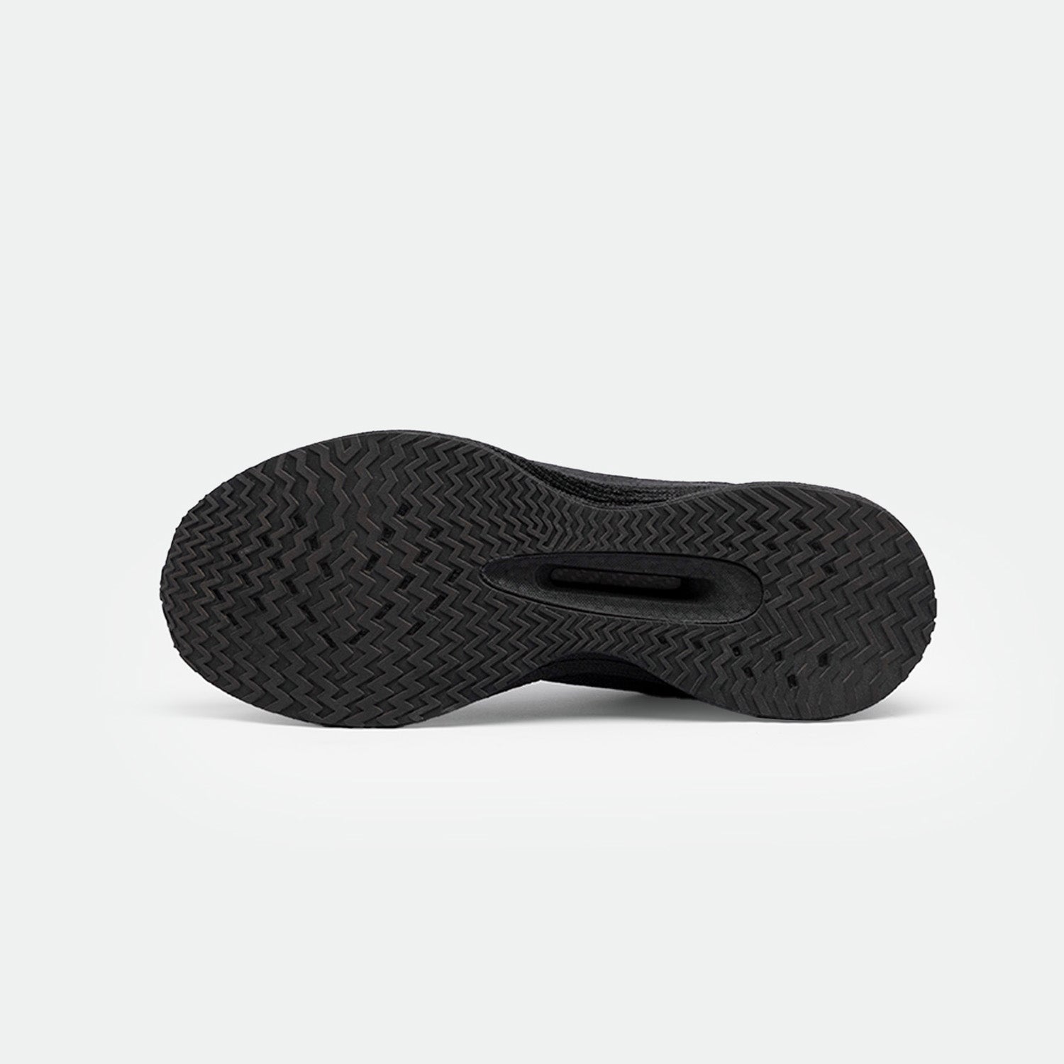 The image shows the sole of a black sneaker with a textured, herringbone pattern, providing traction. The tone is sleek and functional on a neutral background.