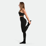 a fit woman stand with pose sports and wearing matching set black bras and legging  with socks 