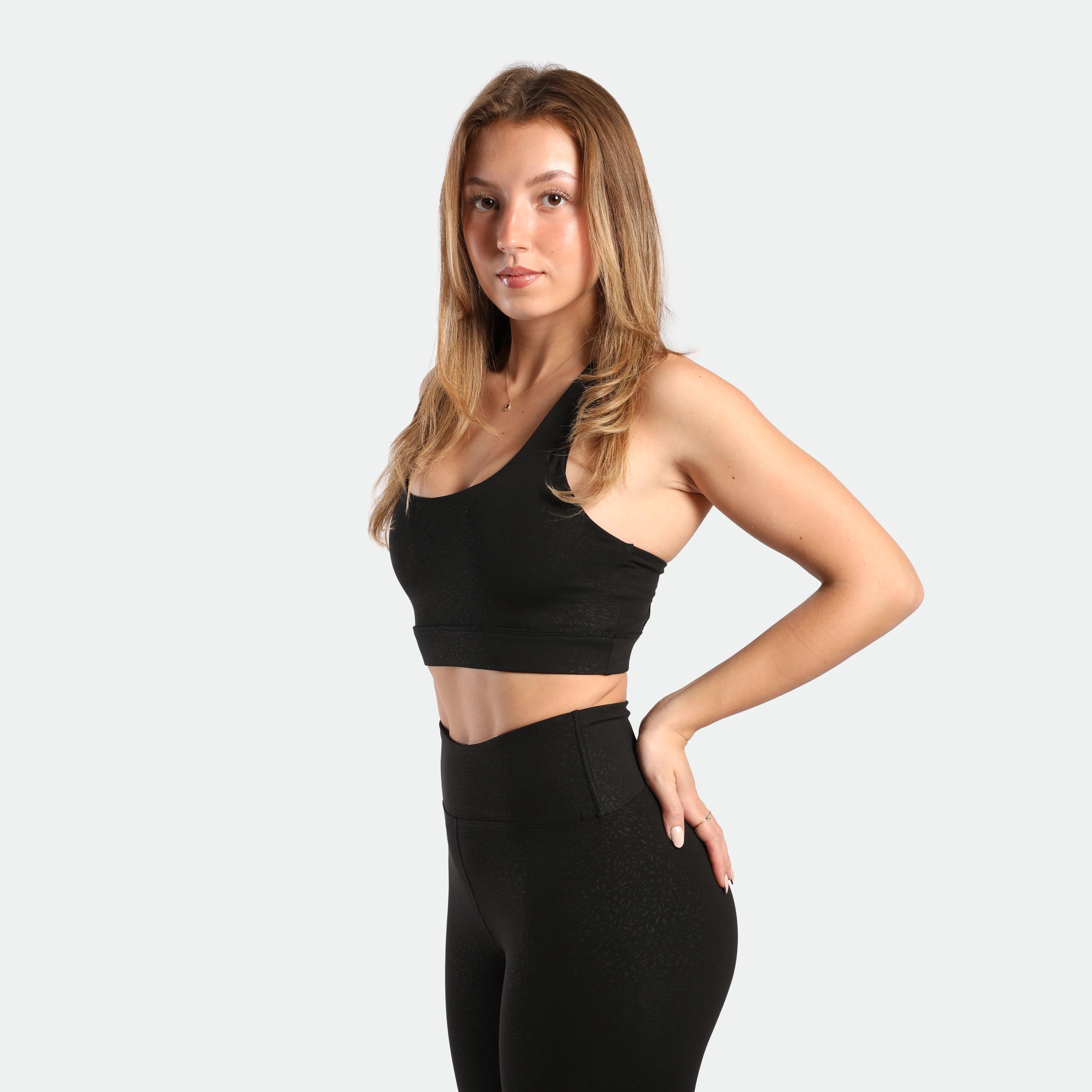 a fit woman stand at right and wearing matching set black ,bra and legging 