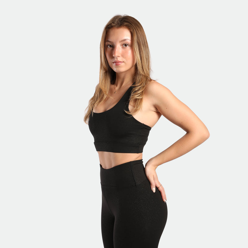 a fit woman stand at right and wearing matching set black ,bra and legging 