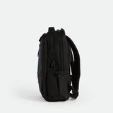 A sleek, black backpack is shown standing upright on its base, viewed from the side against a plain white background. The design is minimalist with subtle zippers and padded shoulder straps visible.