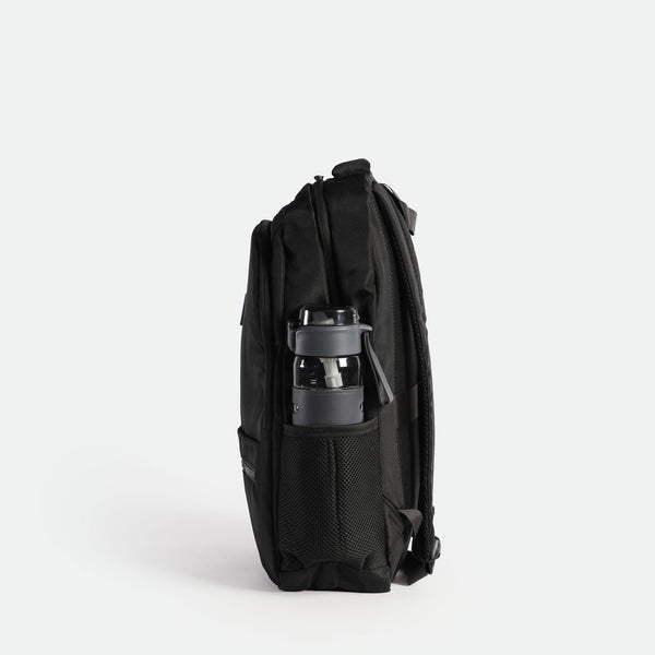 A black backpack with a mesh side pocket containing a black and gray water bottle. The backpack is shown from a side view, highlighting its multiple compartments and sleek design