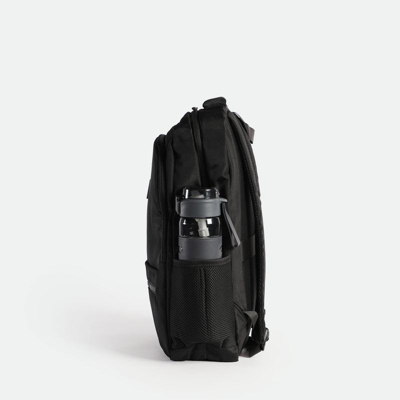 A black backpack with a mesh side pocket containing a black and gray water bottle. The backpack is shown from a side view, highlighting its multiple compartments and sleek design