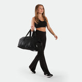 a fit woman wearing matching set black ,bra and flared  legging , plus shoes  and bag 