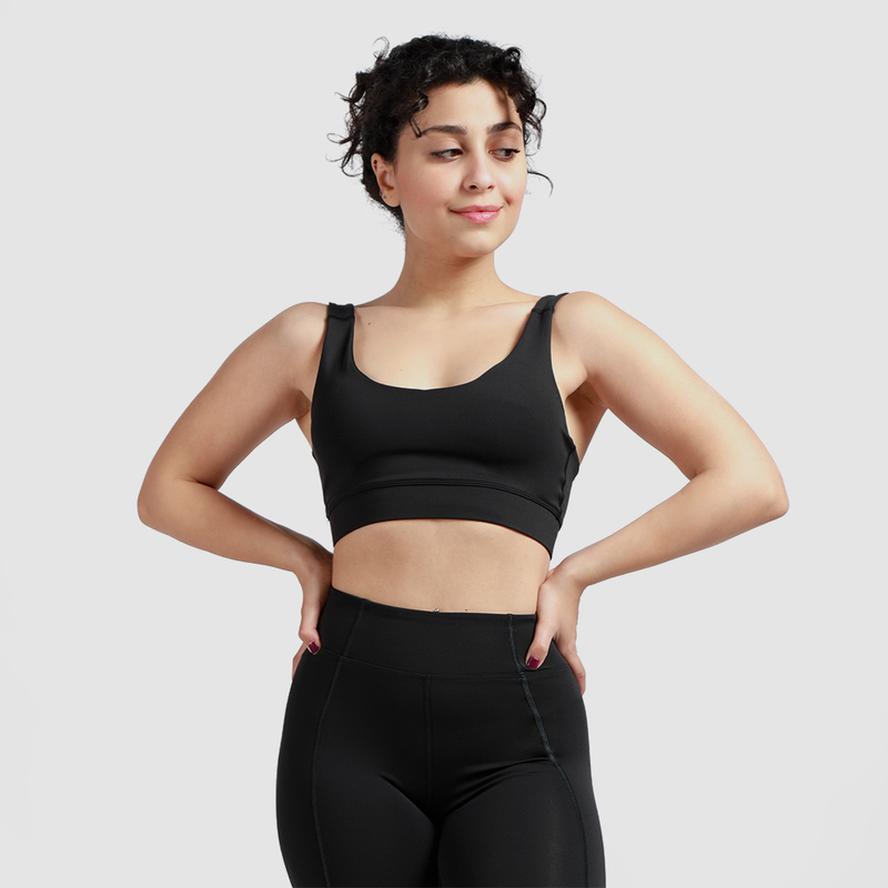 Woman wearing matching bra and leggings, standing and looking to the right, light gray background