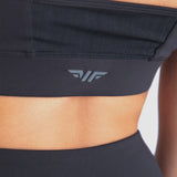 Close-up of woman's back wearing a black sports bra, featuring a subtle logo on the back, white logo (winnerforce)