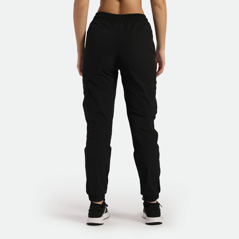 a back view for fit woman wearing black cargo pants with shoes ,plus the  background is light grey 