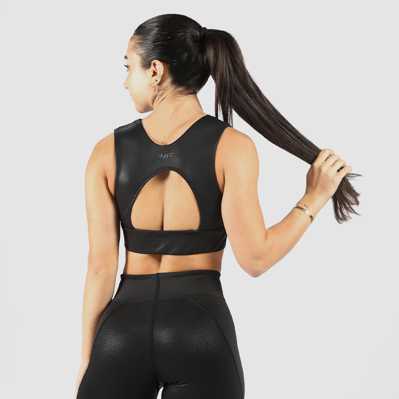 Back view of a woman wearing a black faux leather sports bra and leggings, with a custom bra design and logo, and a light gray background