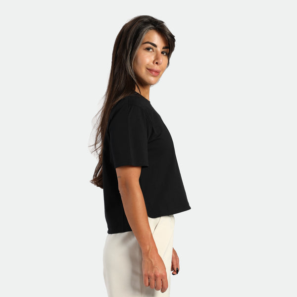 Woman wearing a black t-shirt and white pants on a plain background