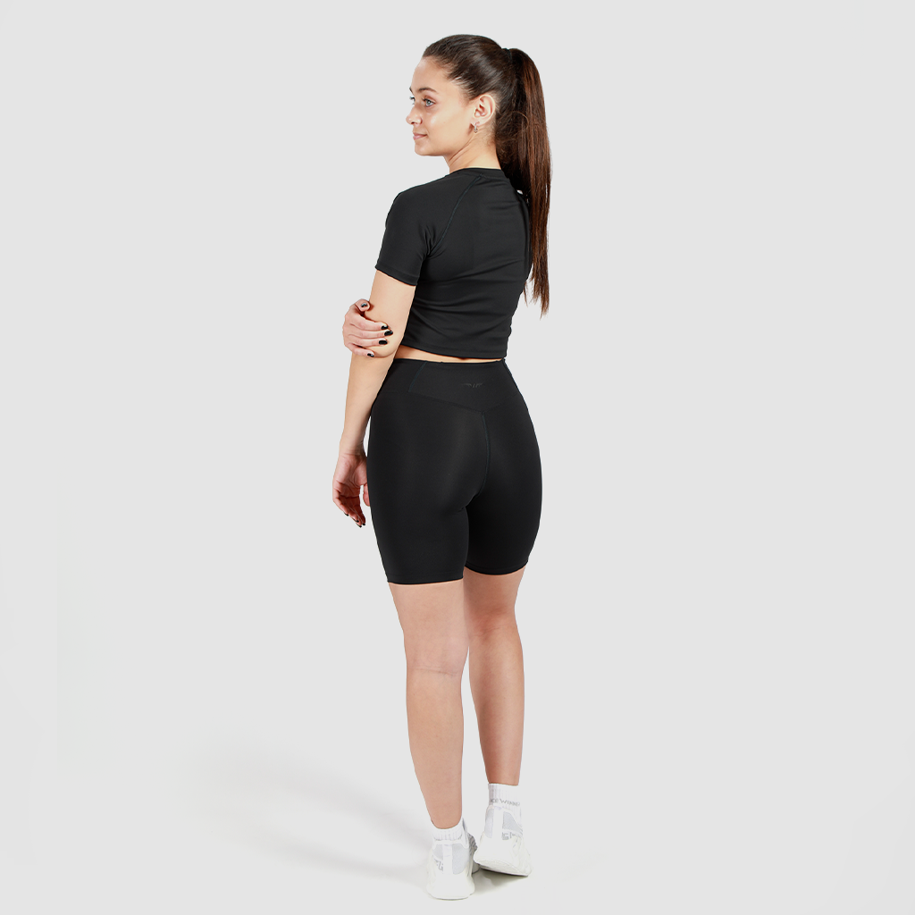 a back view for fit woman wearing  crop top with short black and sneakers white 
