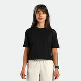 Woman wearing a black t-shirt and white pants on a plain background