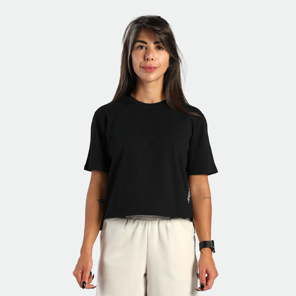 Woman wearing a black t-shirt and white pants on a plain background
