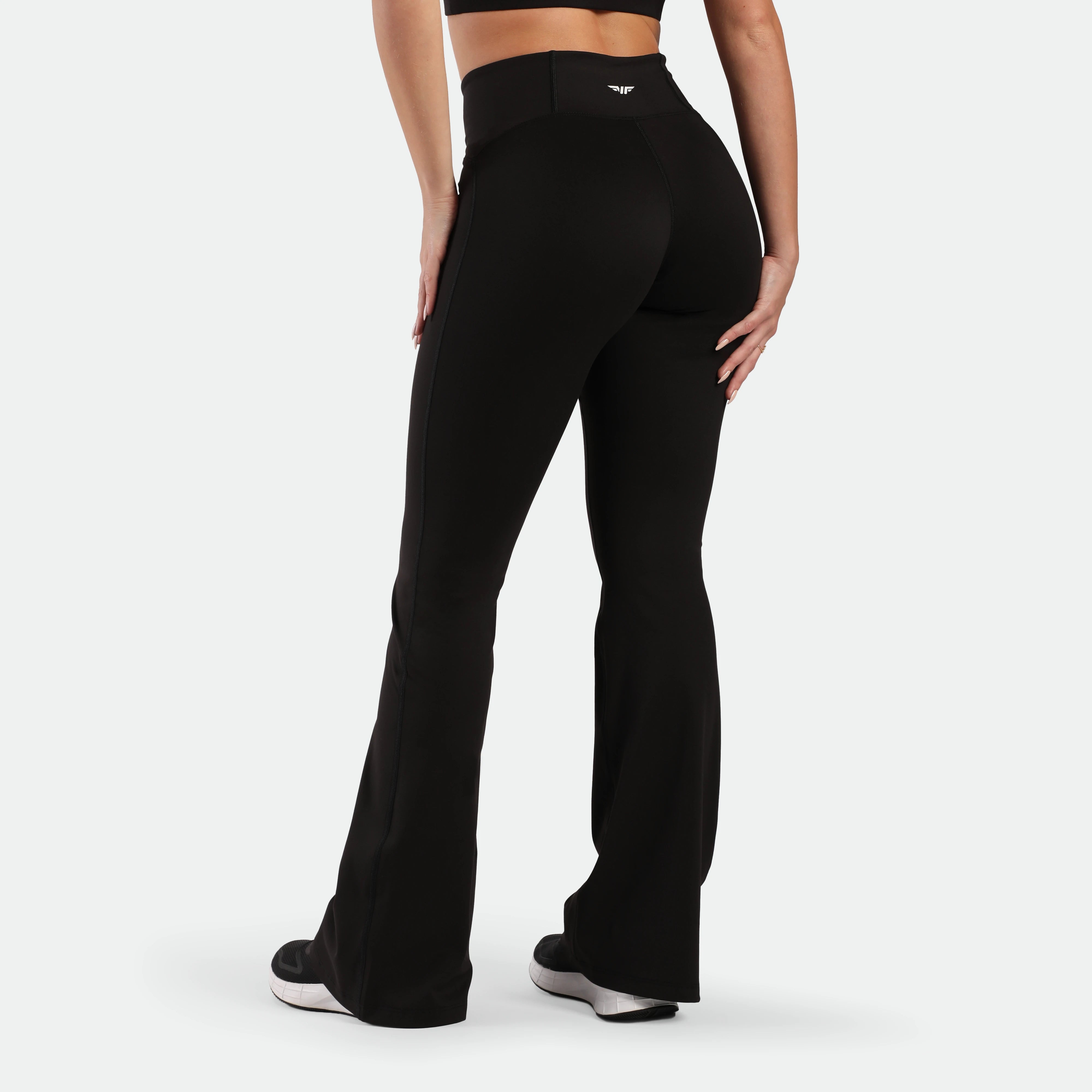 a  back view for woman wearing flared legging black ,plus the shoes 