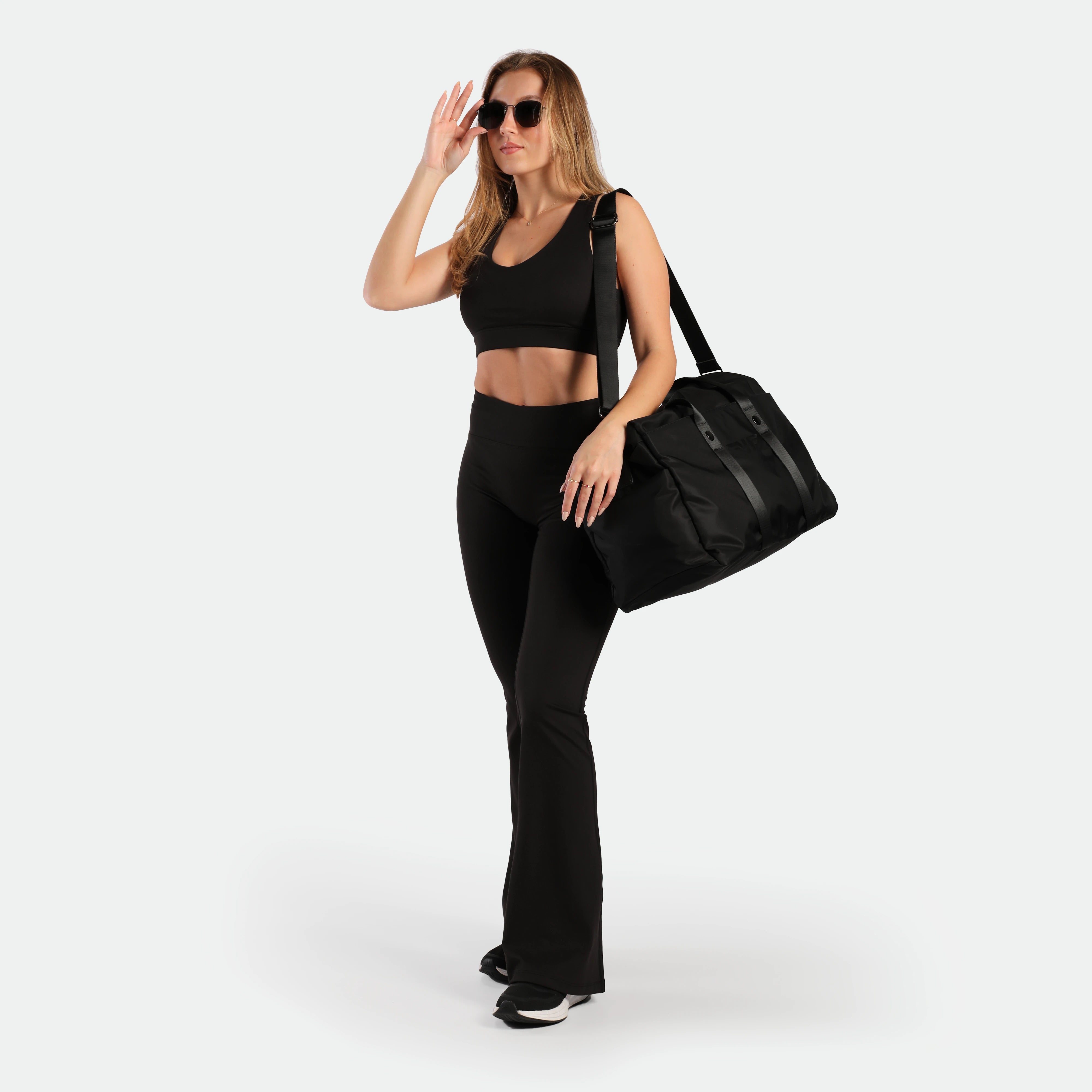 a slim woman stand with pose and wearing set black ,bra and flared legging ,plus the shoes 